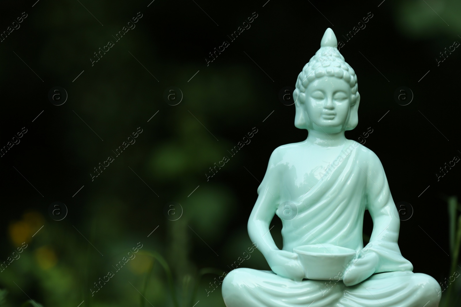 Photo of Decorative Buddha statue on blurred background outdoors. Space for text