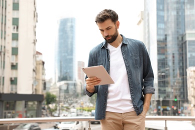 Photo of Handsome man working with tablet on city street