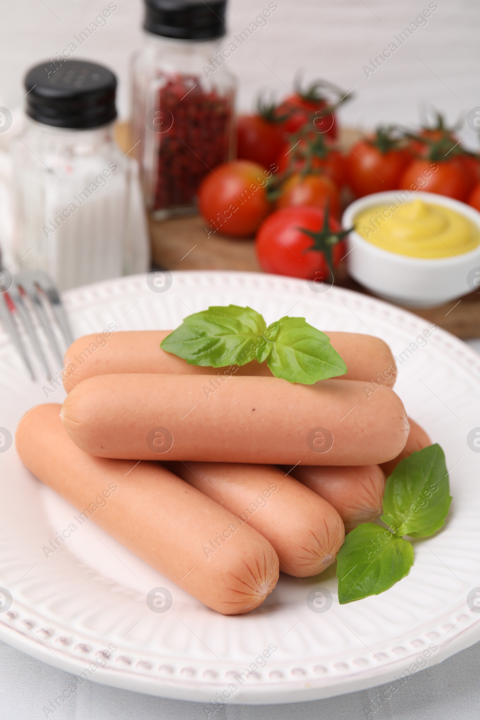 Photo of Delicious boiled sausages and basil on table, closeup