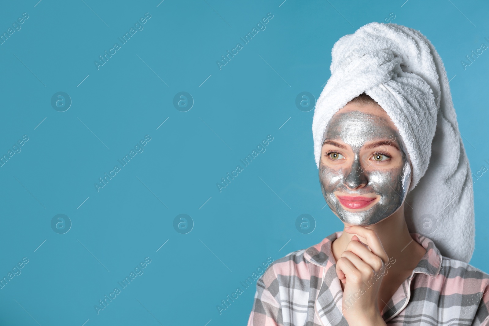 Photo of Young woman with cleansing mask on her face against color background, space for text. Skin care