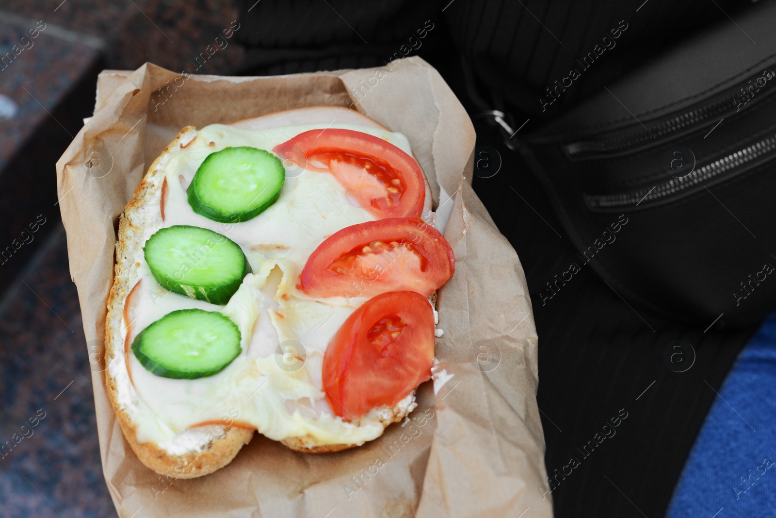 Photo of Woman holding tasty sandwich with vegetables outdoors, closeup. Street food