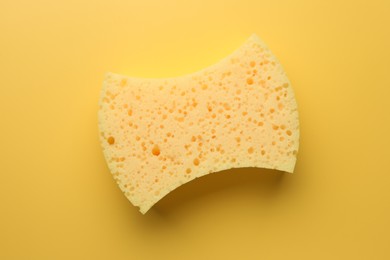 Photo of New sponge on yellow background, top view