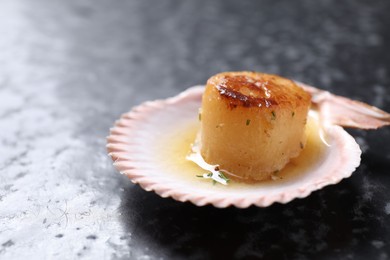 Photo of Delicious fried scallop in shell on black table, closeup. Space for text