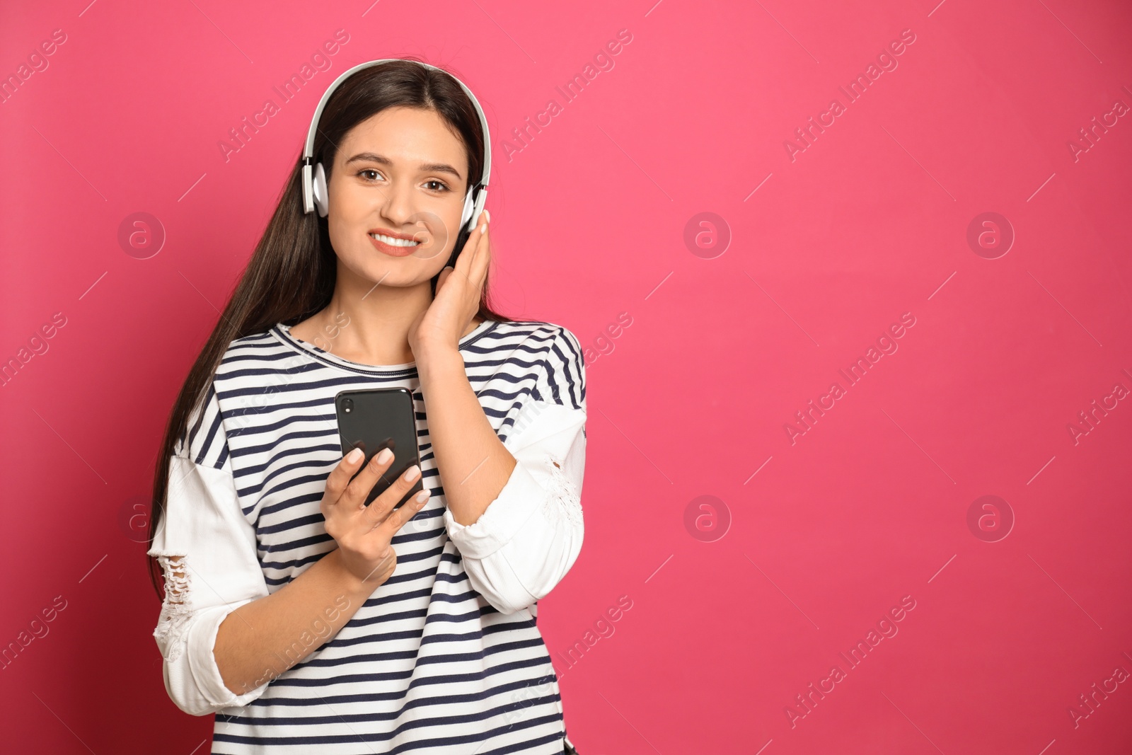 Photo of Young woman listening to audiobook on pink background. Space for text