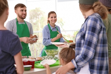 Photo of Volunteers serving food for poor people indoors