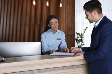 Receptionist registering client at desk in lobby