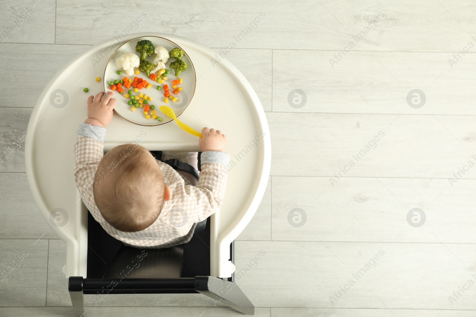 Photo of Cute little baby eating healthy food, top view. Space for text