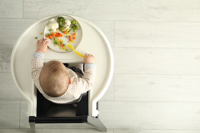 Photo of Cute little baby eating healthy food, top view. Space for text