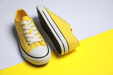 Photo of Pair of yellow classic old school sneakers on color background