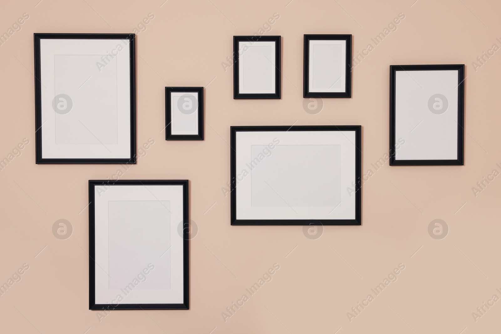 Photo of Different empty frames hanging on beige wall