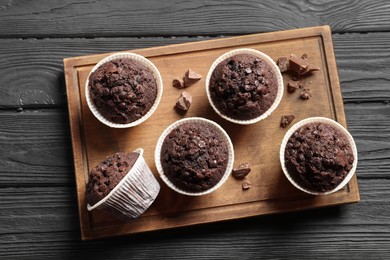 Delicious chocolate muffins on black wooden table, top view