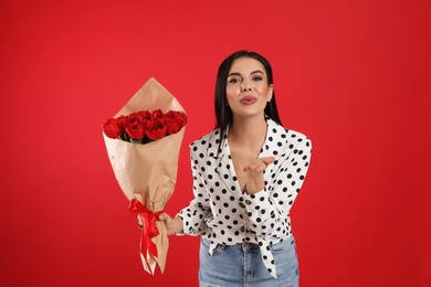 Photo of Happy woman with tulip bouquet on red background. 8th of March celebration