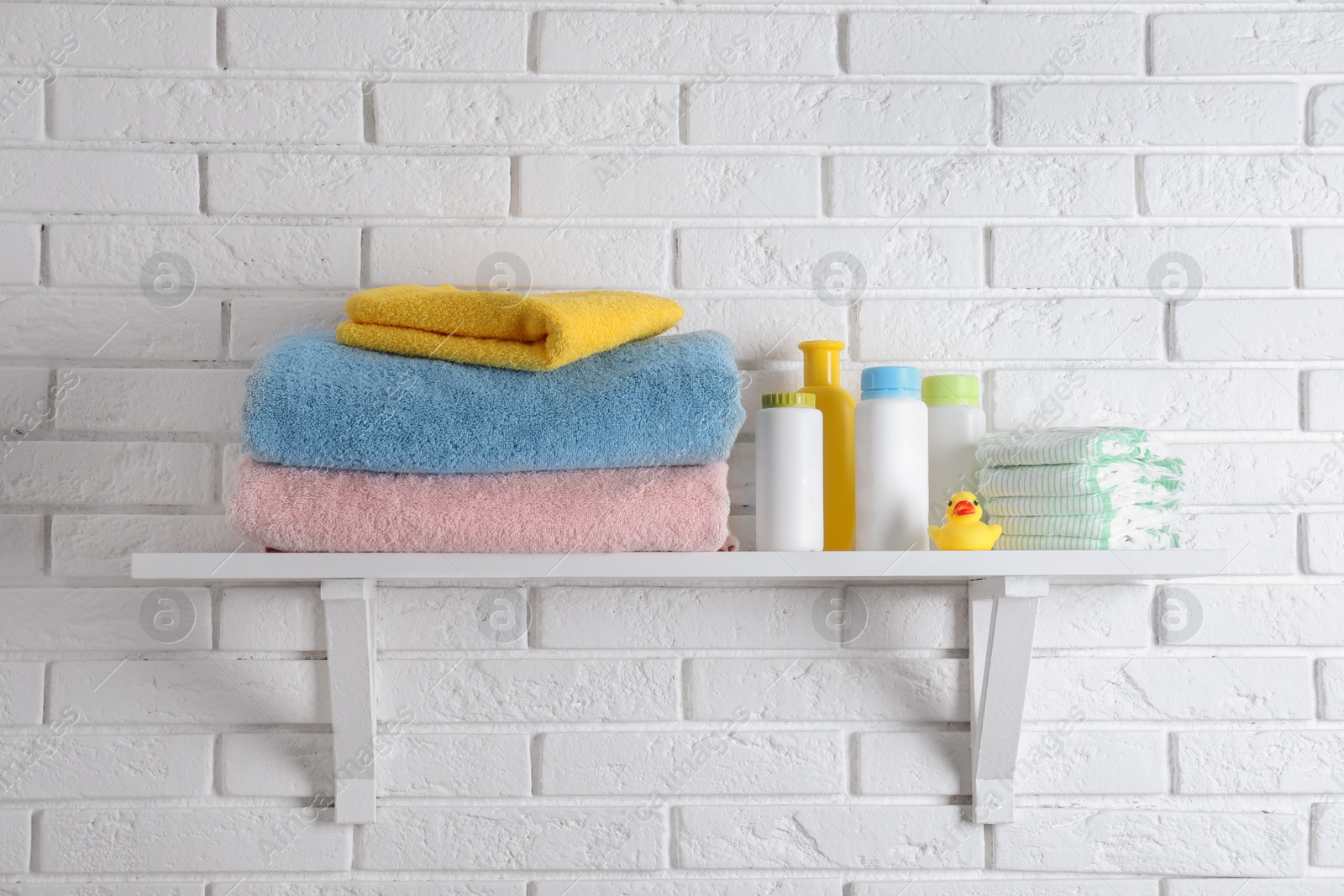 Photo of Shelf with baby accessories on white brick wall