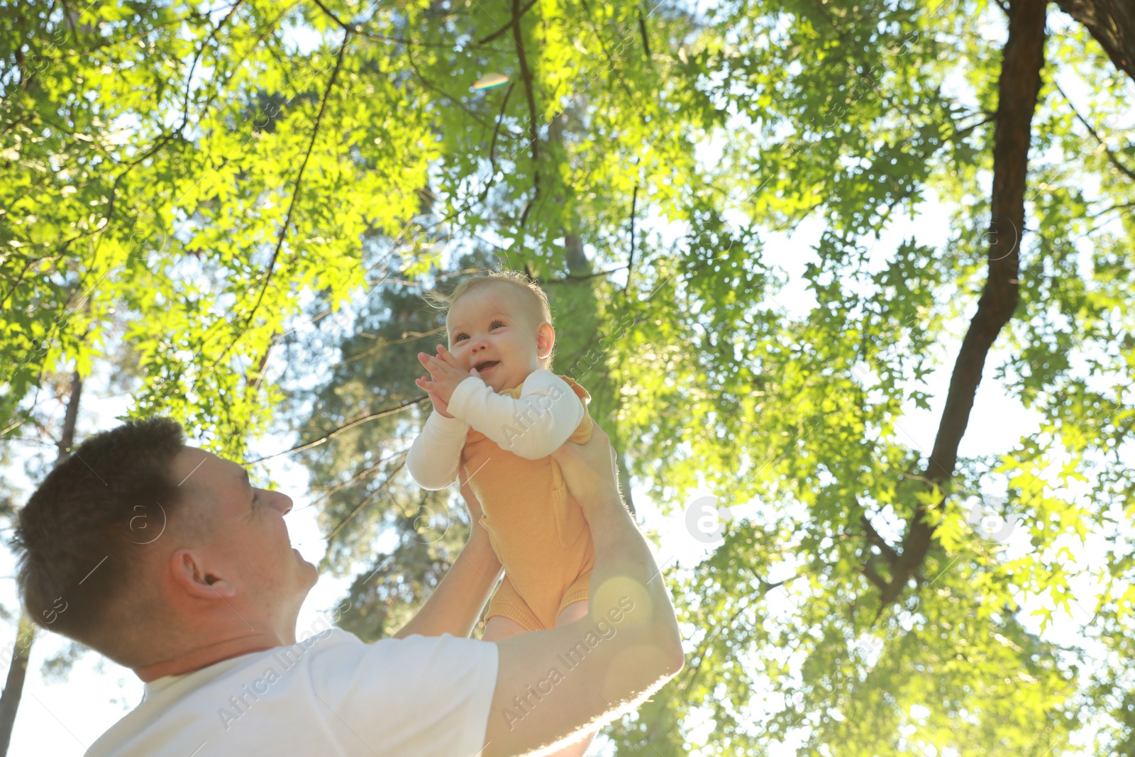 Photo of Father with his cute daughter spending time together in park on summer day, low angle view. Space for text