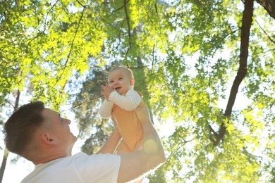 Photo of Father with his cute daughter spending time together in park on summer day, low angle view. Space for text