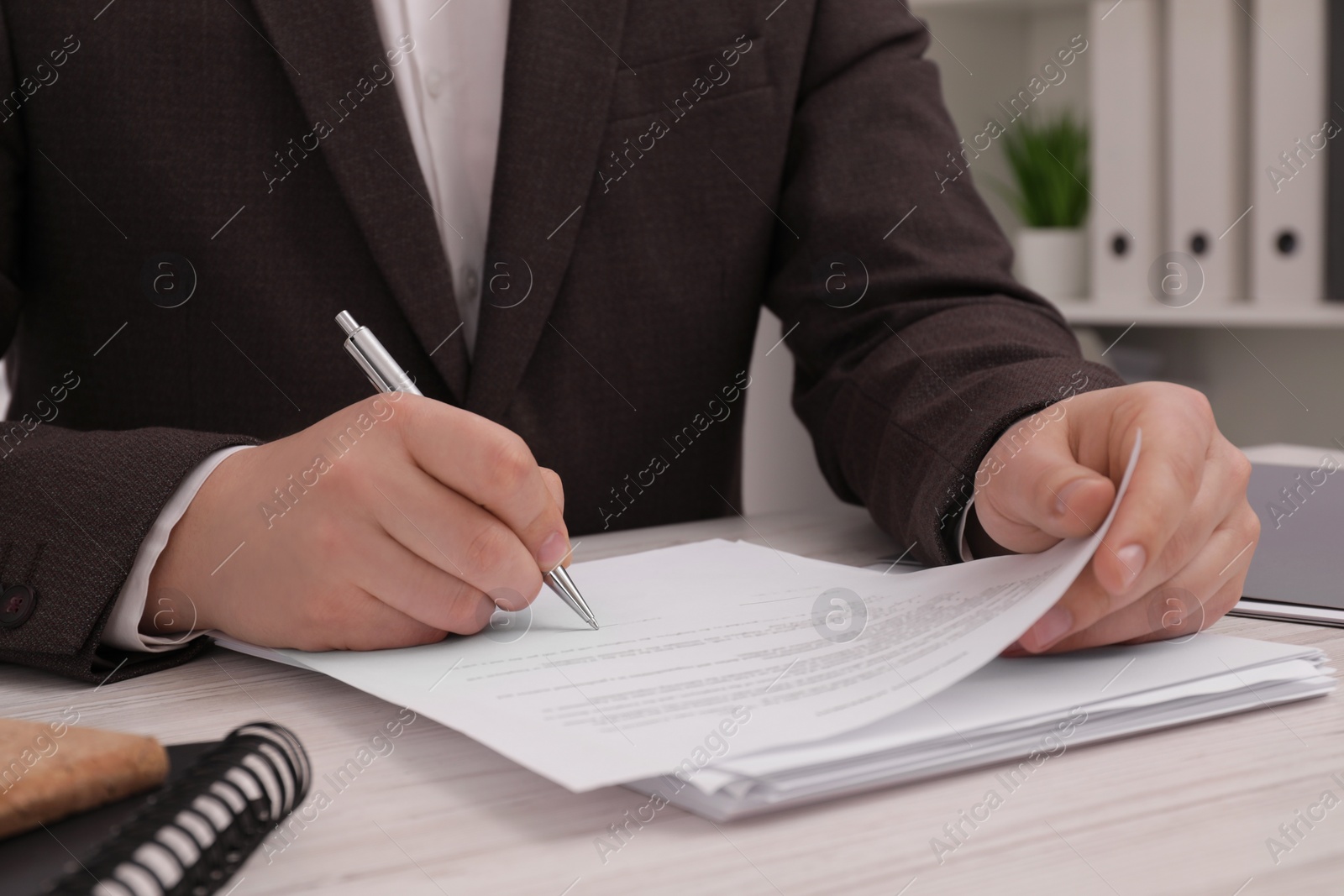 Photo of Man signing document at wooden table, closeup