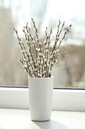 Photo of Beautiful pussy willow branches in vase on window sill indoors