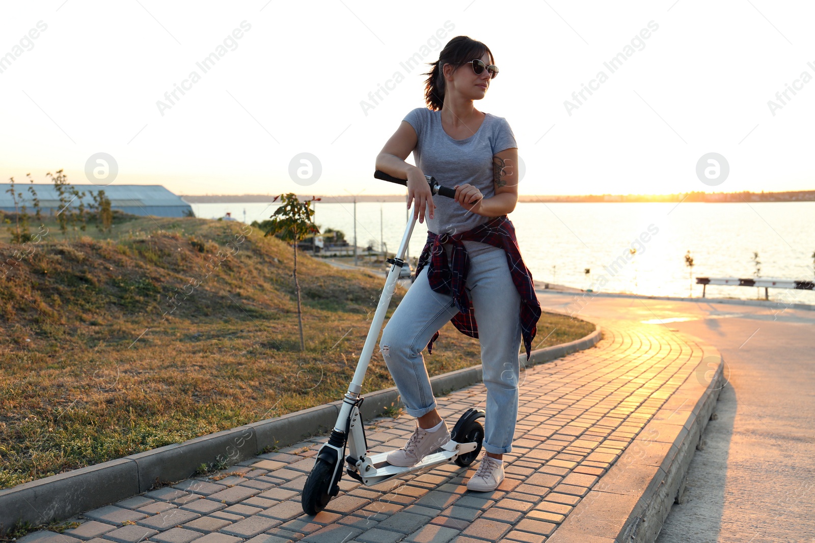 Photo of Young woman with kick scooter on city street