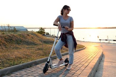 Young woman with kick scooter on city street