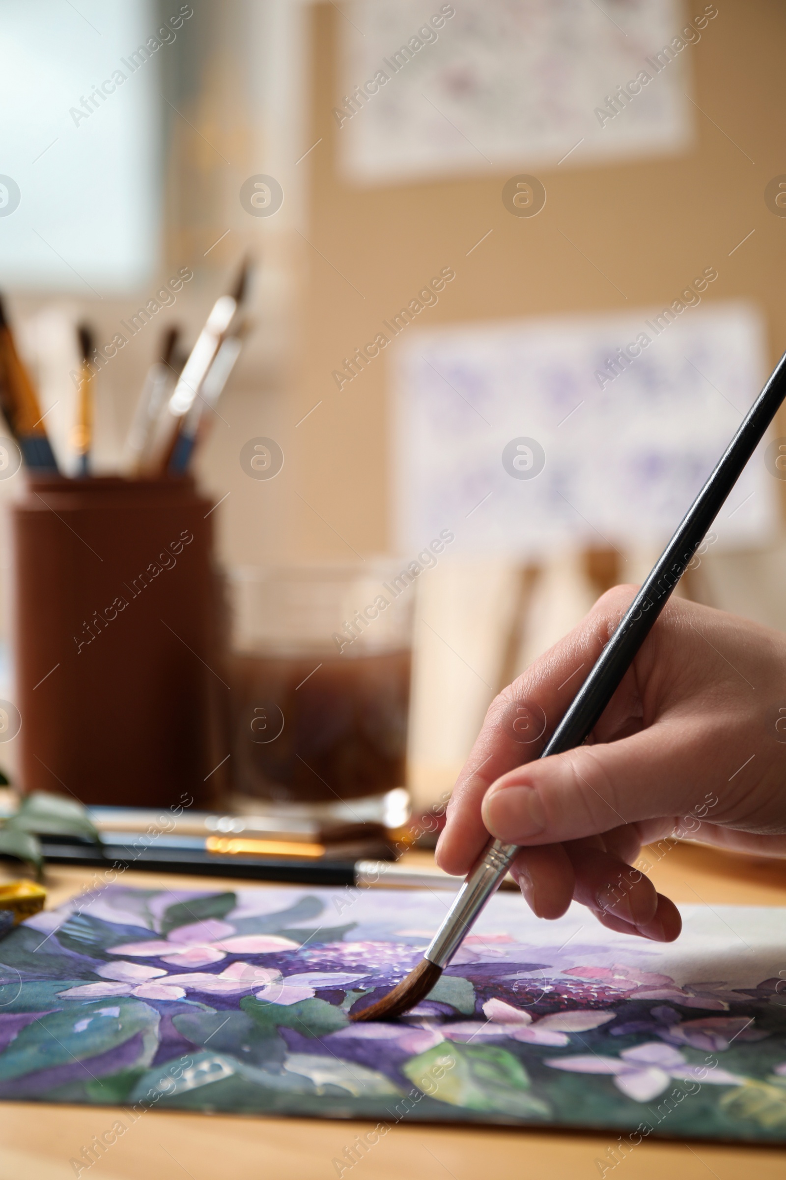 Photo of Woman painting flowers with watercolor at table in workshop, closeup. Space for text