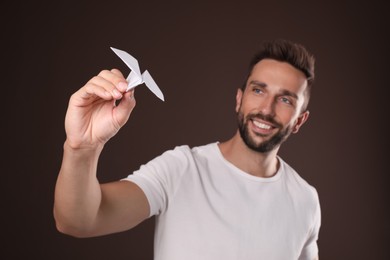 Photo of Handsome man playing with paper plane on brown background
