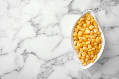 Photo of Bowl with corn kernels on marble background, top view. Space for text