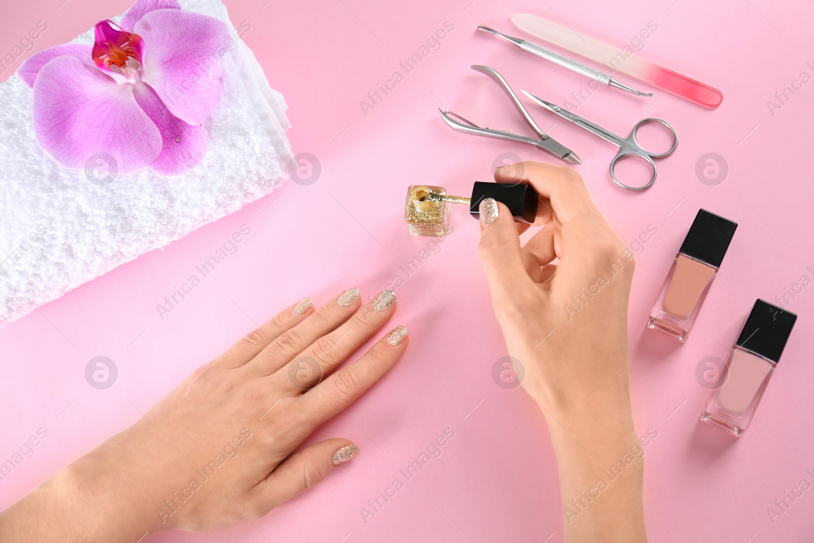 Photo of Woman applying nail polish on color background, above view