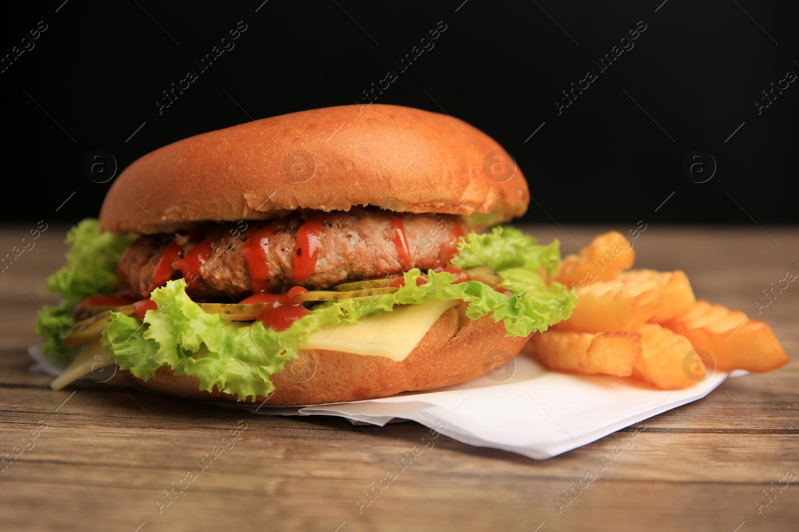 Photo of Tasty burger with french fries on wooden table, closeup