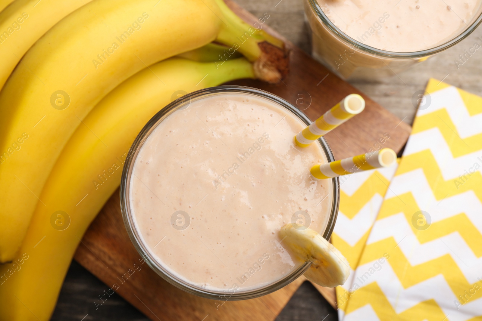 Photo of Glass with banana smoothie on wooden table, flat lay