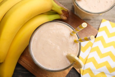 Glass with banana smoothie on wooden table, flat lay