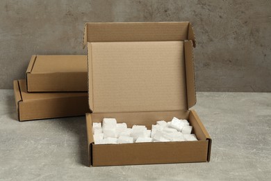 Cardboard boxes with pieces of polystyrene foam on grey textured table
