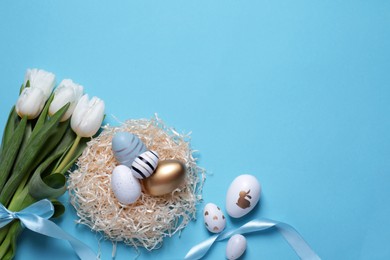 Photo of Many painted Easter eggs, tulip flowers and ribbon on light blue background, flat lay. Space for text