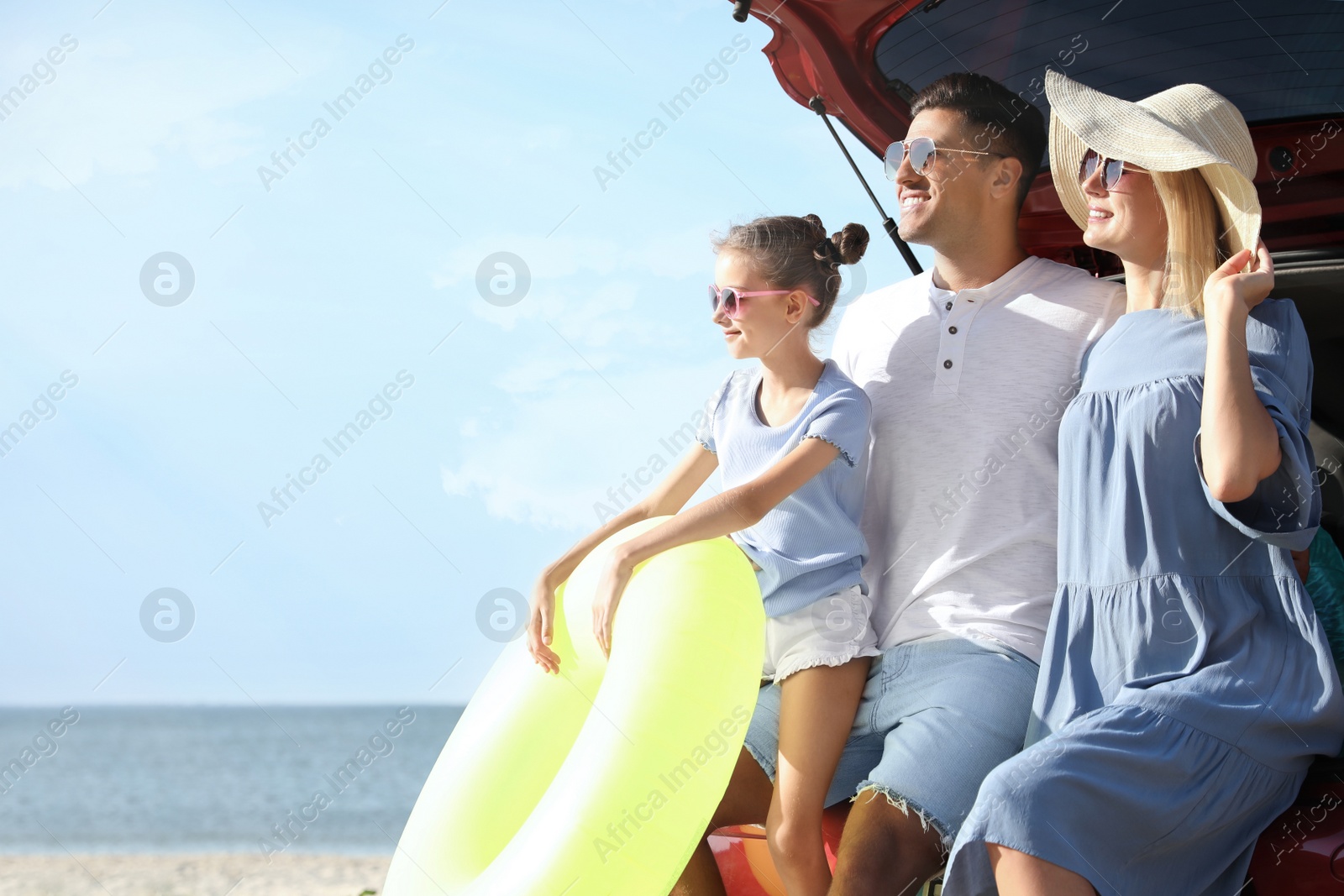 Photo of Happy family with inflatable ring near car at beach on sunny day