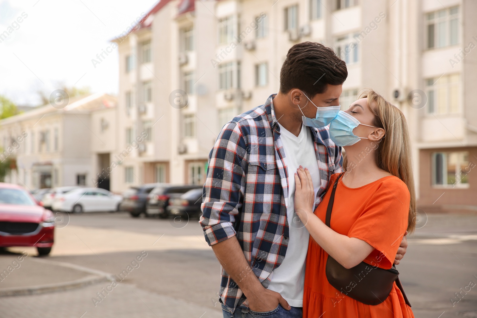 Photo of Couple in medical masks trying to kiss outdoors