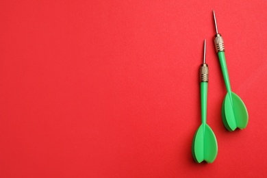 Photo of Green dart arrows on red background, flat lay with space for text