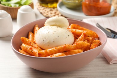 Photo of Bowl of delicious pasta with burrata and tomato sauce on white wooden table
