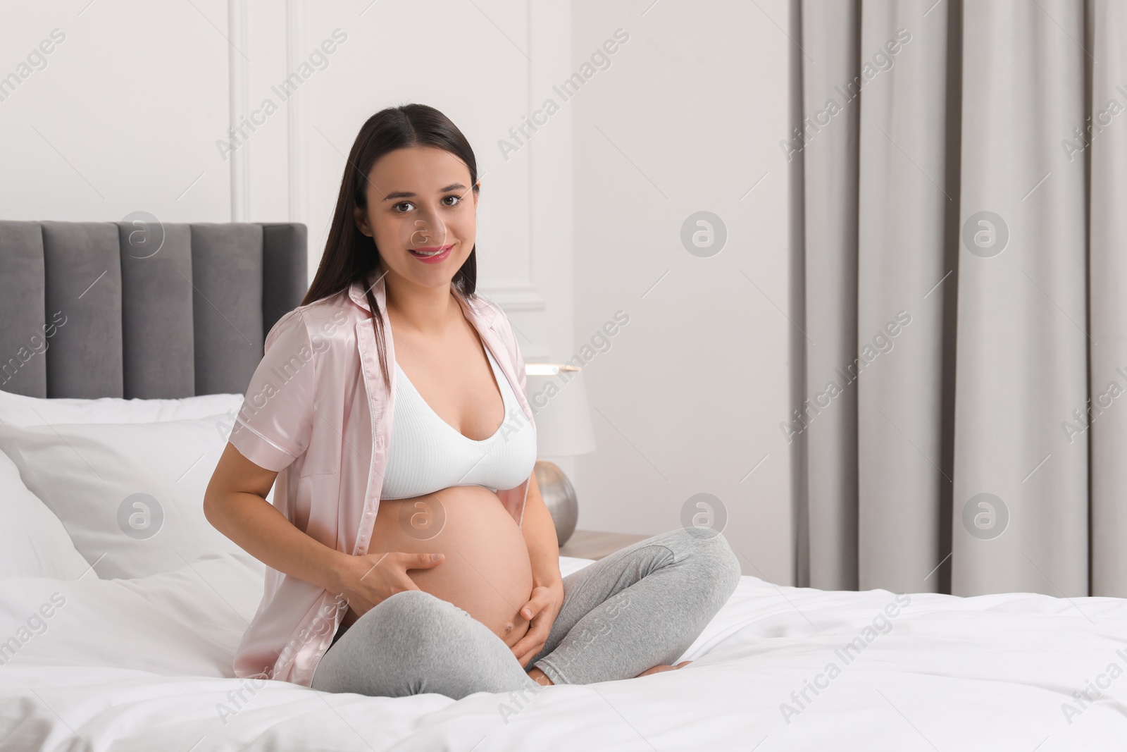 Photo of Beautiful pregnant woman on bed at home