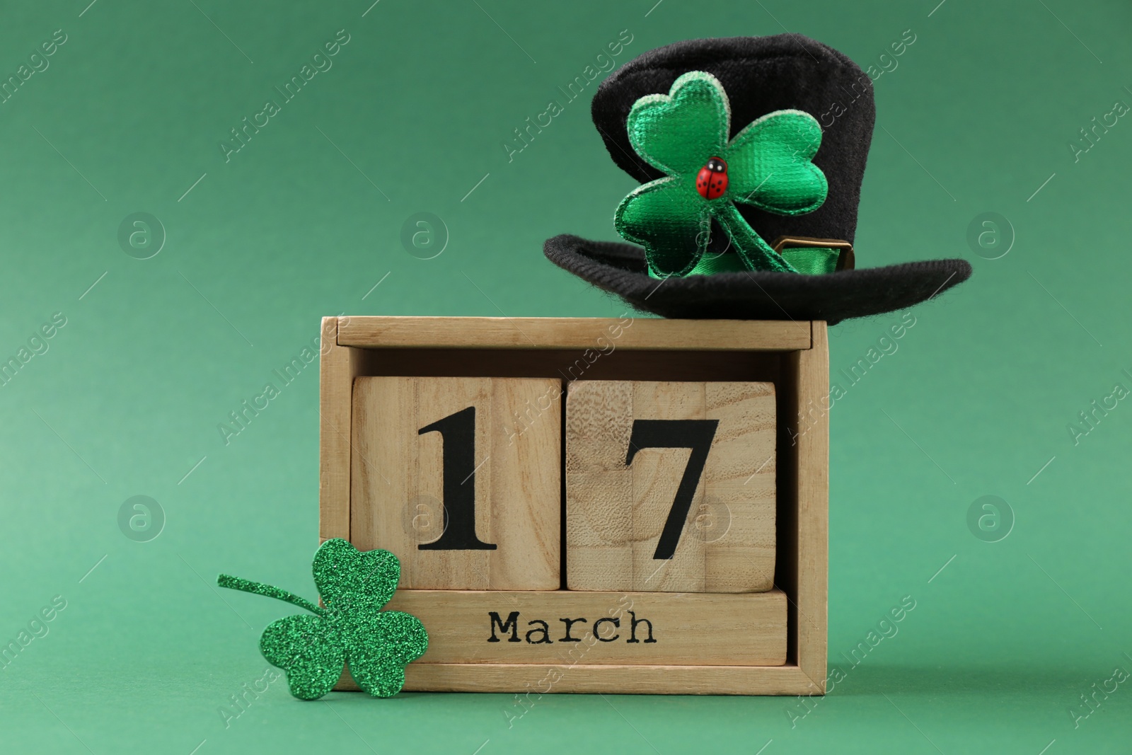 Photo of St. Patrick's day - 17th of March. Block calendar, leprechaun hat and decorative clover leaf on green background