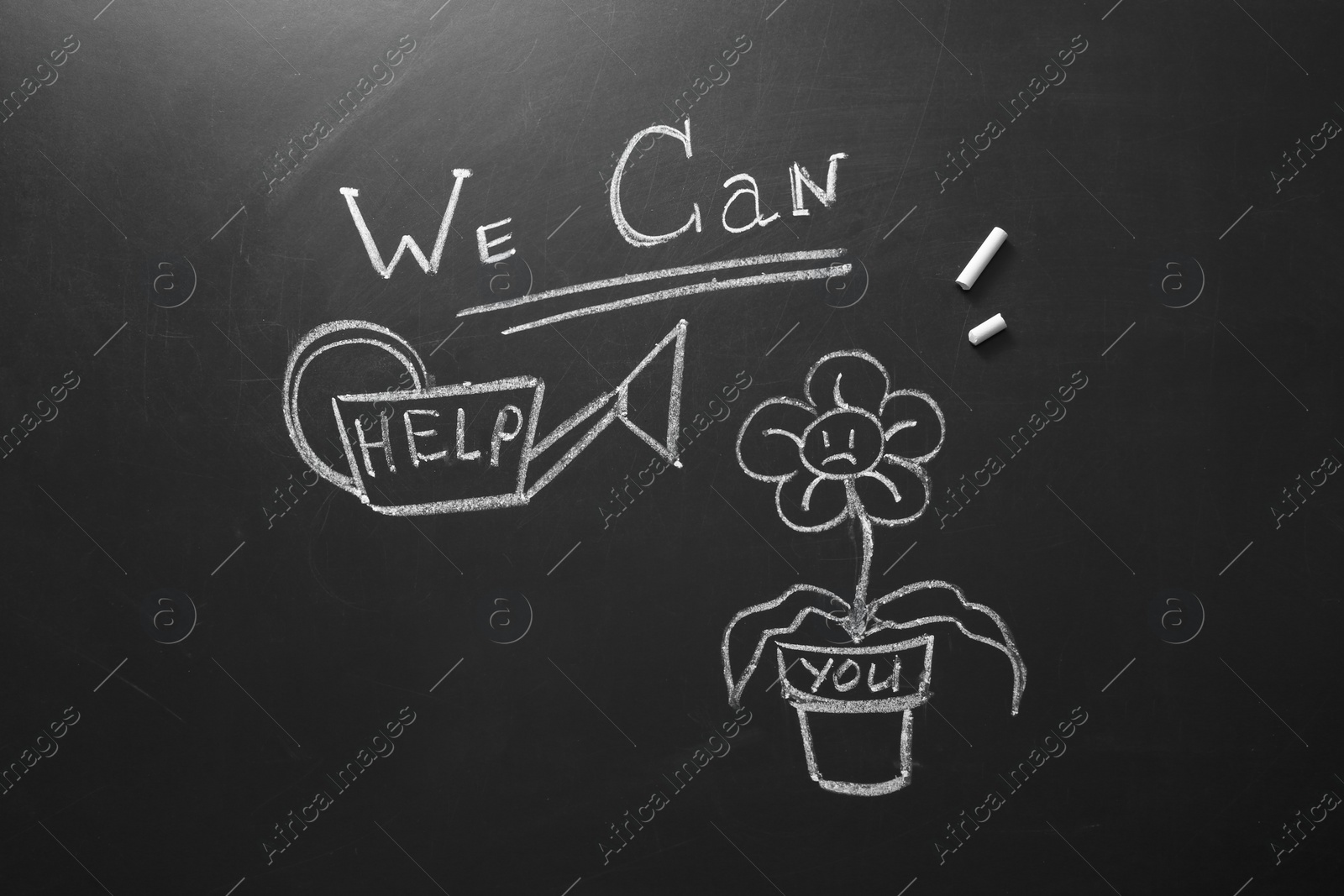 Photo of Drawing of flower, watering can and phrase "We can help" on chalkboard, top view