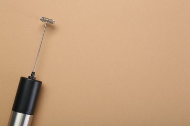 Milk frother wand on light brown background, top view. Space for text