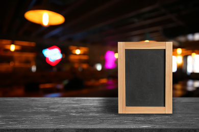 Blank small blackboard on wooden table in cafe, mockup for menu design 