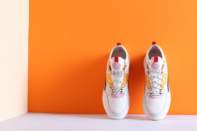 Photo of Pair of stylish sneakers near color wall, space for text