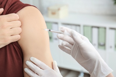 Photo of Doctor vaccinating male patient in clinic, closeup