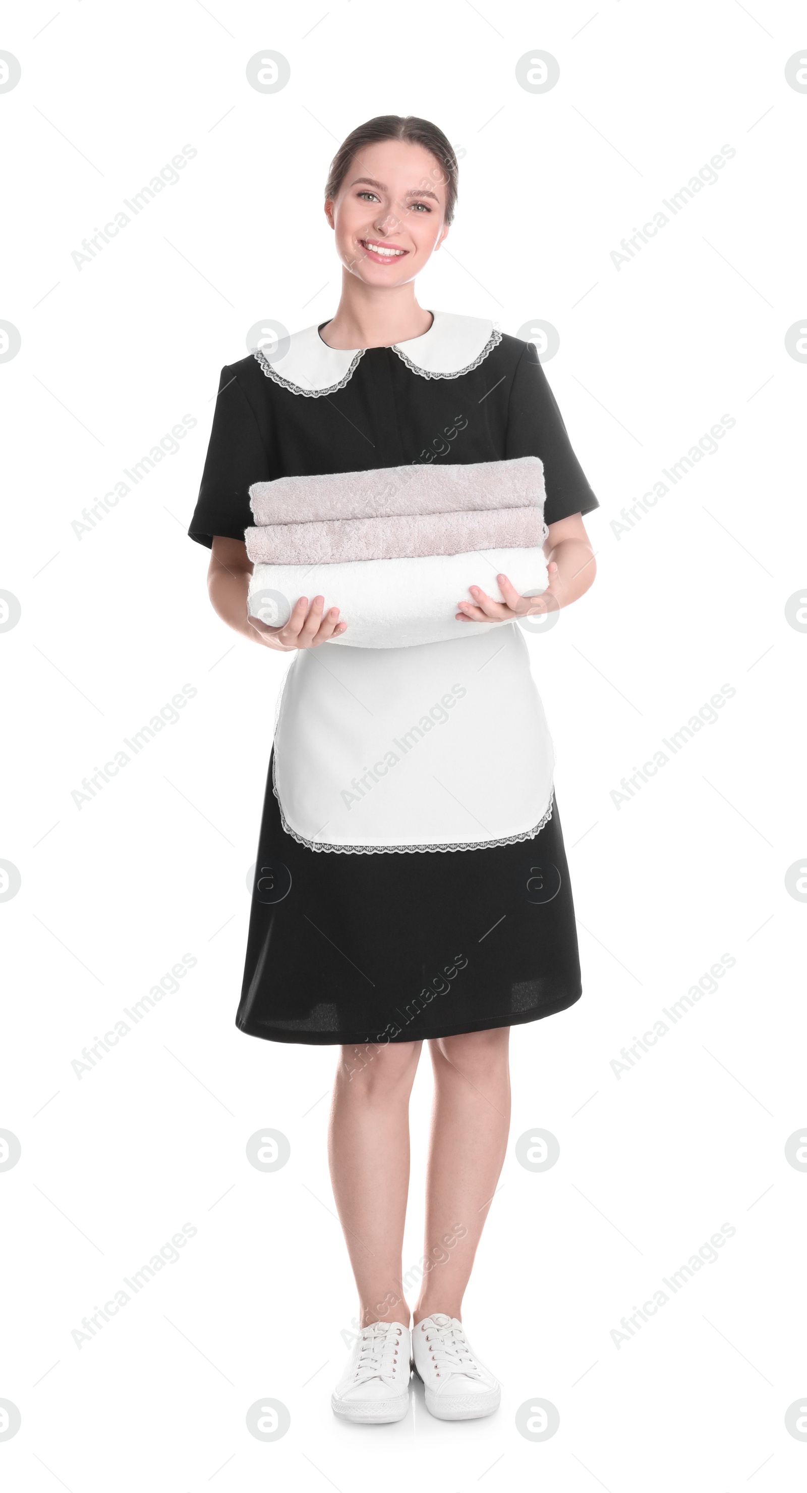 Photo of Young chambermaid holding stack of fresh towels on white background