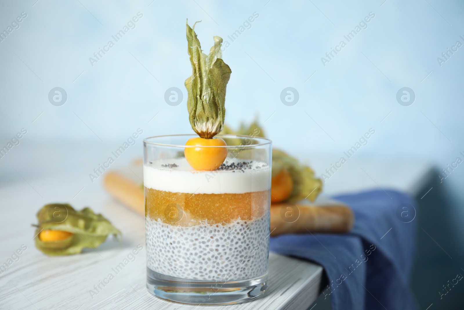 Photo of Delicious chia pudding decorated with physalis fruit on white wooden table