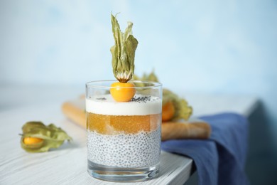 Delicious chia pudding decorated with physalis fruit on white wooden table