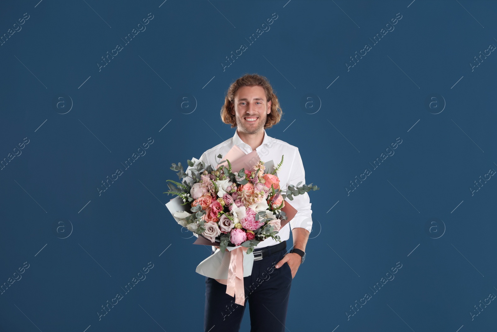 Photo of Young handsome man with beautiful flower bouquet on blue background