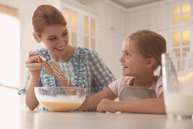 Photo of Mother and daughter making dough together in kitchen