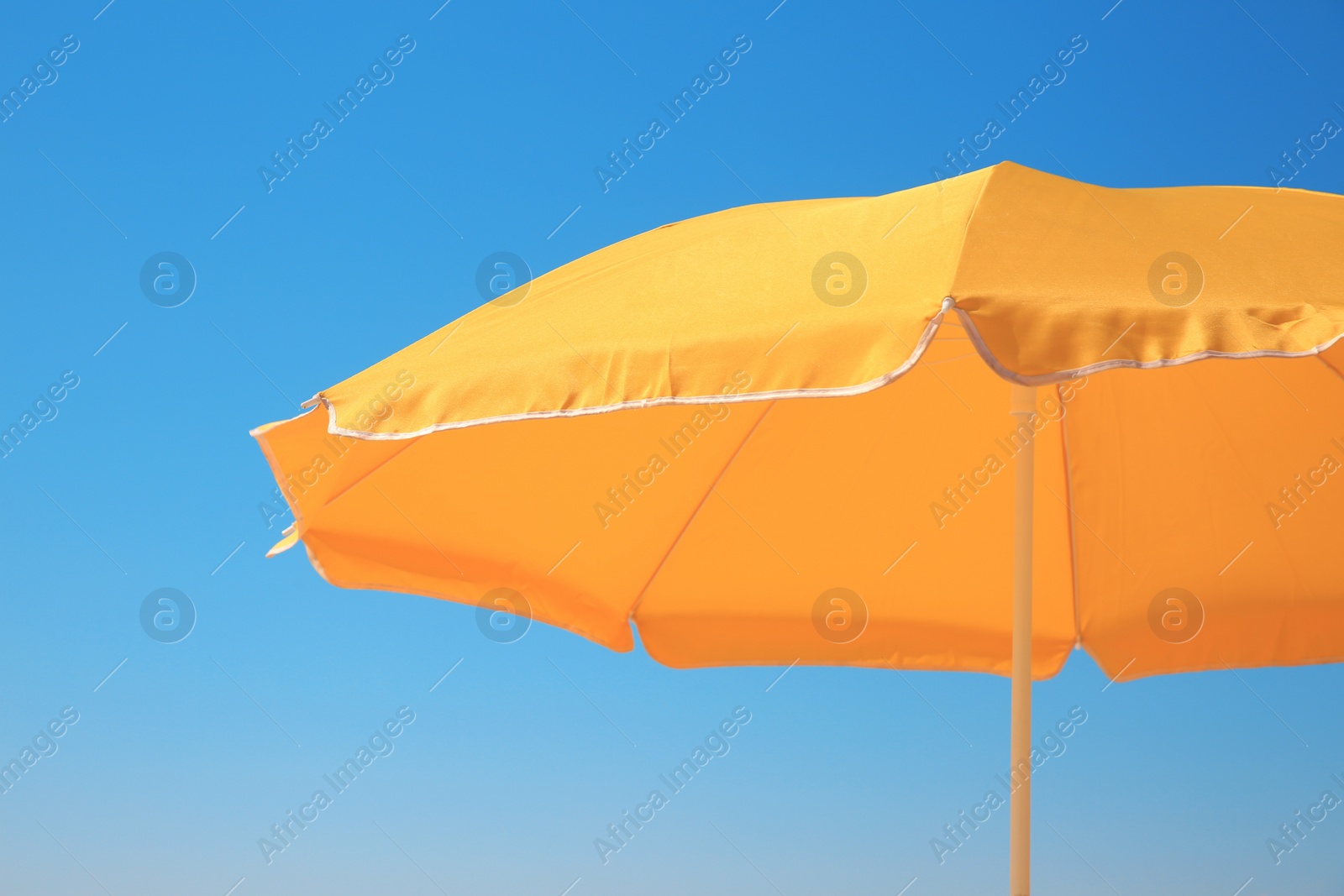 Photo of Orange beach umbrella against blue sky on sunny day