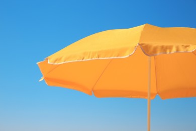 Orange beach umbrella against blue sky on sunny day